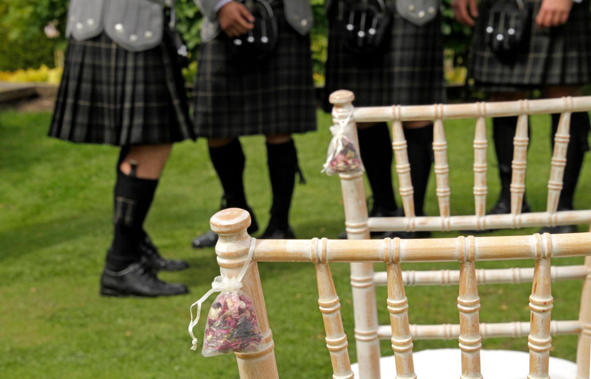 Scottish wedding setup with chairs decorated with confetti bags and pipers wearing traditional kilts in the background